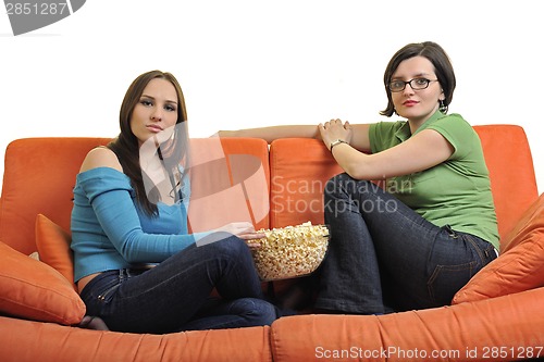 Image of female friends eating popcorn and watching tv at home