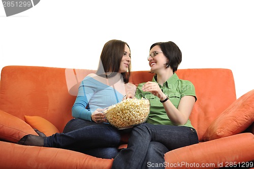 Image of female friends eating popcorn and watching tv at home