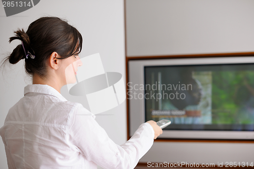 Image of young woman watching tv at home