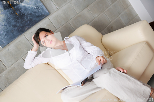 Image of woman reading magazine at home