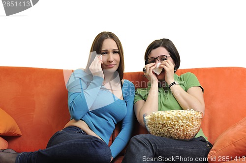 Image of female friends eating popcorn and watching tv at home