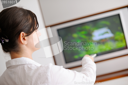 Image of young woman watching tv at home