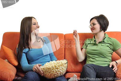 Image of female friends eating popcorn and watching tv at home