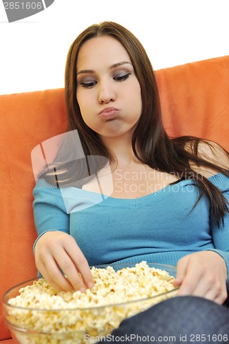 Image of young woman eat popcorn and watching tv