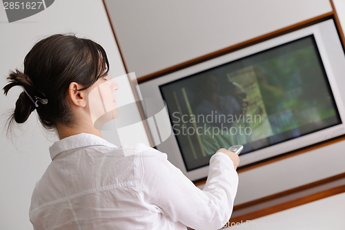 Image of young woman watching tv at home