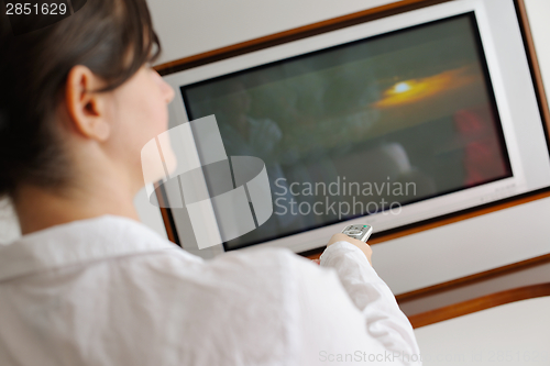 Image of young woman watching tv at home