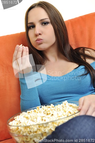 Image of young woman eat popcorn and watching tv