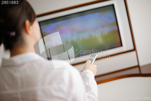 Image of young woman watching tv at home