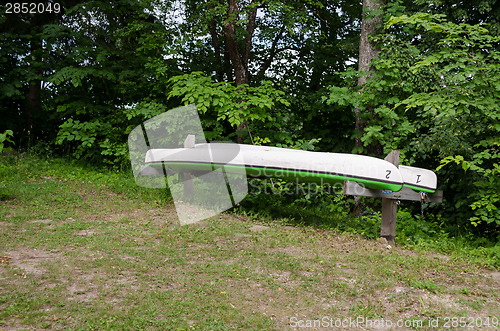 Image of inverted canoes on wooden sticks dug into ground 