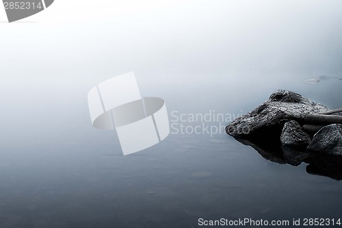 Image of Reflections of rocks in a foggy lake