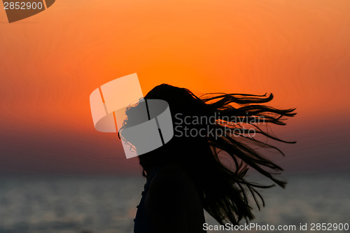 Image of Abstract of woman tossing hair at sunset 