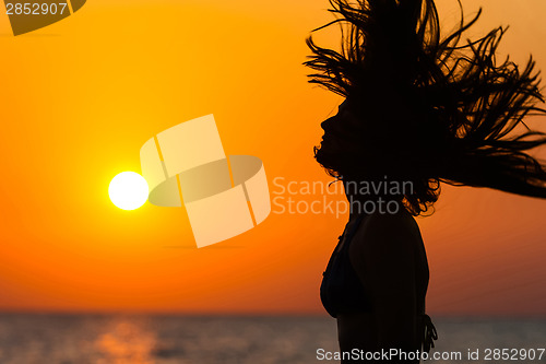 Image of Silhouette of woman waving hair at sunset