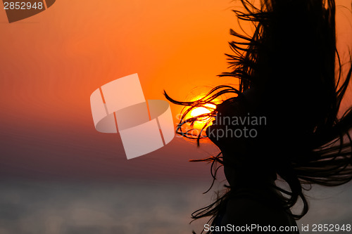 Image of Silhouette of young woman waving hair at sunset