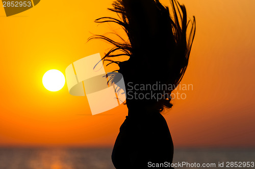 Image of Woman tossing hair at sunset