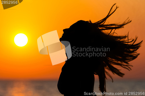 Image of Woman waving hair at sunset