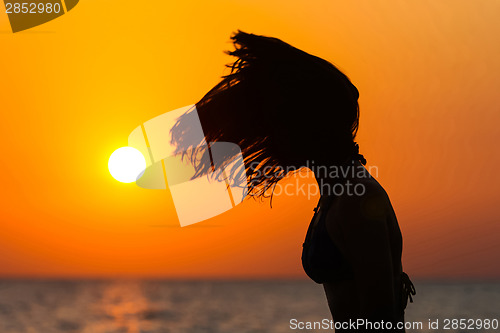 Image of Young woman tossing hair at sunset