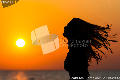 Image of Young woman waving hair at sunset