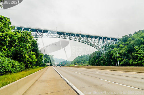 Image of steel bridge over highway on cloudy day in the mountains