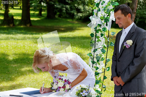 Image of beautiful blonde smiling bride signed contract