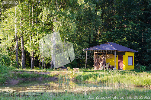 Image of rustic steam bathhouse to green birch forest 