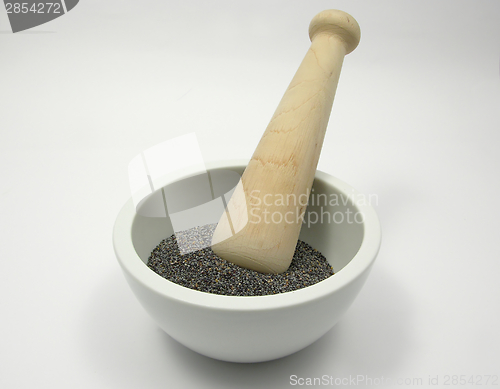 Image of Pestling poppy seeds  in a bowl of chinaware