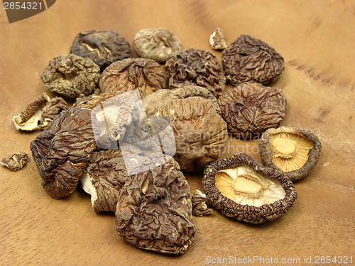 Image of Dried shiitake arranged on a brown wooden plate