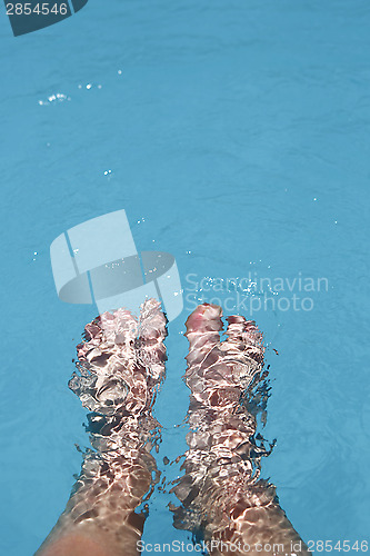 Image of Splashing female feet in a swimming pool