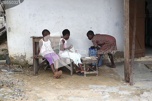 Image of African girls sit in front of a house