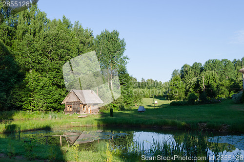 Image of countryside with wooden bathhouse and green nature 