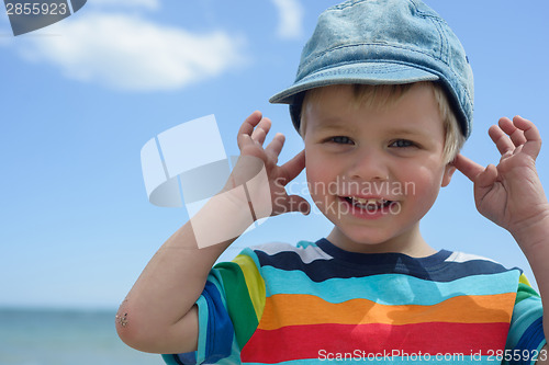 Image of Small boy holds his hands over ears not to hear