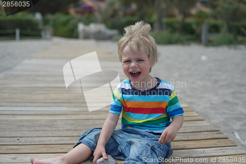 Image of Flashy boy sits on a wooden walkway on the beach