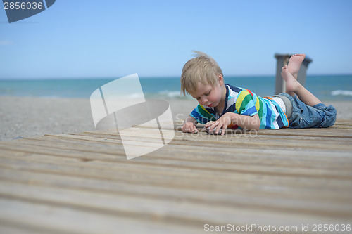 Image of Boy resting on a wooden walkway on the beach