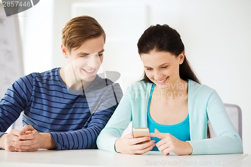 Image of two smiling students with smartphone at school