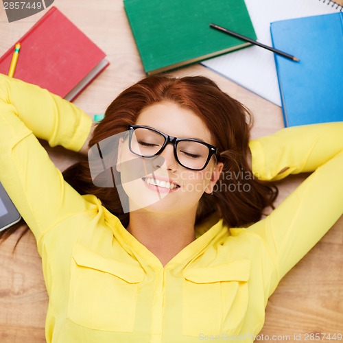 Image of smiling student in eyeglasses lying on floor