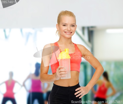 Image of smiling sporty woman with protein shake bottle