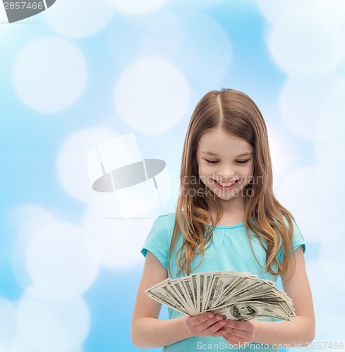 Image of smiling little girl looking at dollar cash money