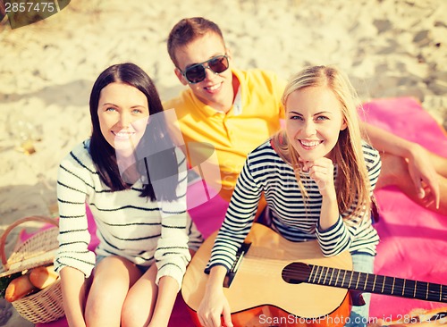 Image of group of friends with guitar having fun on beach