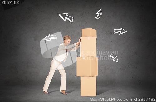 Image of businesswoman pushing tower of cardboard boxes