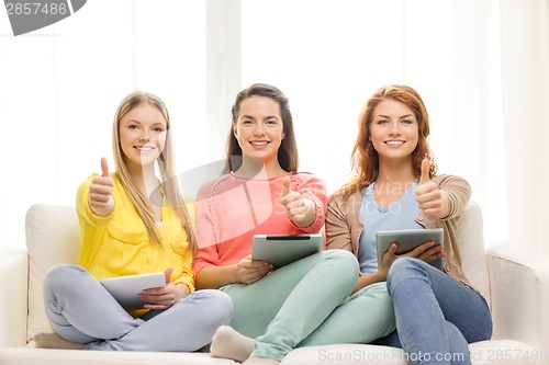 Image of three smiling teenage girls with tablet pc at home