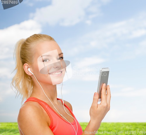 Image of smiling sporty woman with smartphone and earphones