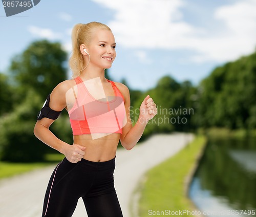 Image of sporty woman running with smartphone and earphones