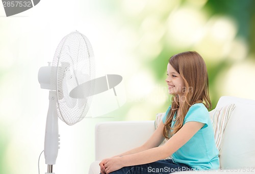 Image of smiling little girl with big fan at home