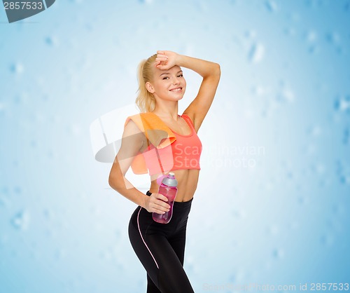 Image of smiling sporty woman with towel and water bottle