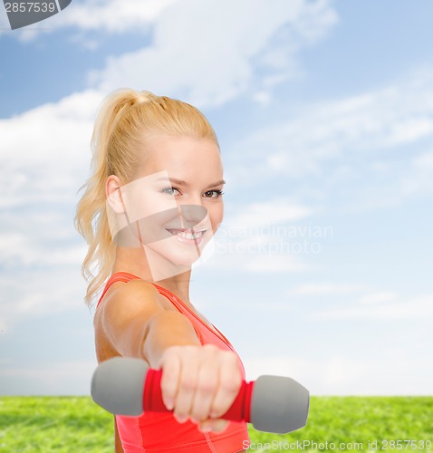 Image of smiling beautiful sporty woman with dumbbell