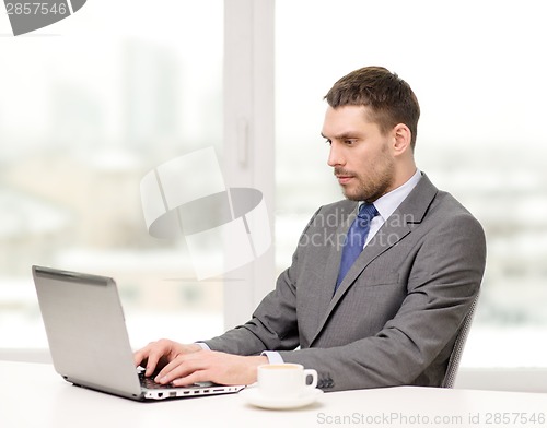 Image of busy businessman with laptop and coffee