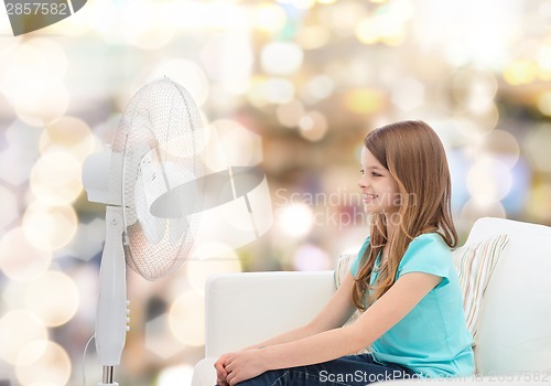 Image of smiling little girl with big fan at home