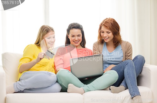 Image of smiling teenage girls with laptop and credit card