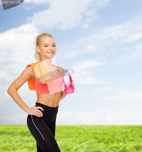 Image of smiling sporty woman with water bottle and towel