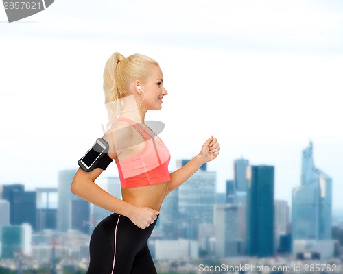 Image of sporty woman running with smartphone and earphones