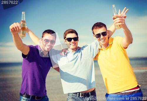 Image of male friends on the beach with bottles of drink